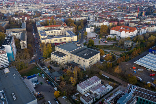 Aerial view of the iconic Berghain nightclub nestled among autumn-toned trees and buildings, a stark contrast of industrial architecture against the city's skyline, Berlin, Berlin, Germany.