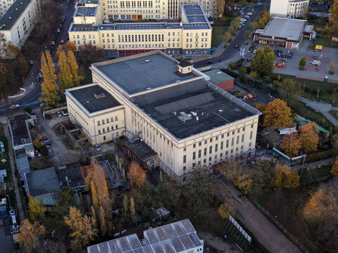 Aerial view of the imposing Berghain, a monolith of concrete and steel, stands in stark contrast to the autumnal hues of the surrounding trees, Berlin, Berlin, Germany.
