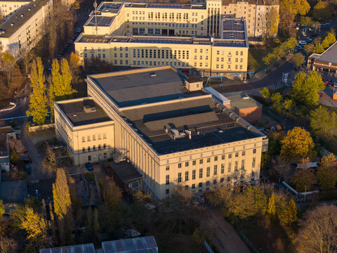 Aerial view of the massive Berghain nightclub, its stark facade contrasting with the autumnal trees surrounding it, Berlin, Berlin, Germany.