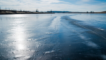 Frozen Lake A Winter Landscape with Blue Ice, Sunlight Reflections, and Distant Trees