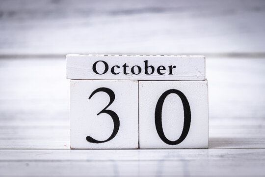 A wooden calendar displaying the date 30 October, symbolizing the approach of Halloween, placed on a textured white surface, capturing seasonal change and celebration.