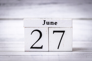 A wooden perpetual calendar displaying the date June 27, perfect for organizing or scheduling...