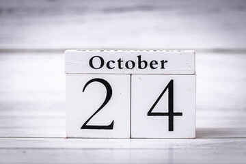 A wooden calendar block displays the date October 24. The clean design emphasizes the simplicity of time management, suitable for themes of organization and planning.