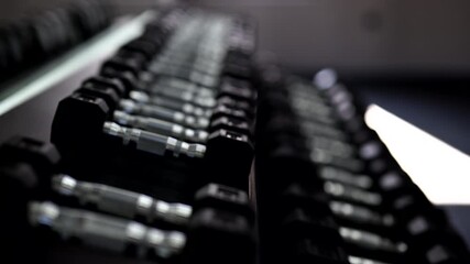 A young woman in a modern gym taking dumbbells from an organized rack before starting her workout. Stylish fitness environment with clean equipment, showcasing strength training and active lifestyle.