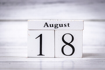 A white wooden calendar displaying the date August 18. Ideal for organizing schedules, planning events, or symbolizing a specific day in August for various purposes.