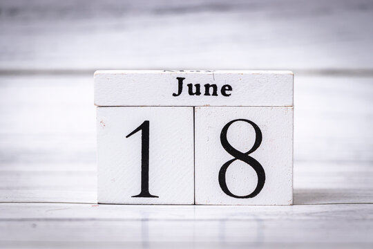 Wooden calendar blocks display the date June 18, representing the middle of the month. Ideal for seasonal themes, events, or planning contexts. Minimalist design.