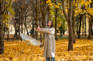 Conceptual portrait of woman in autumn park lifting umbrella with falling yellow maple leaves