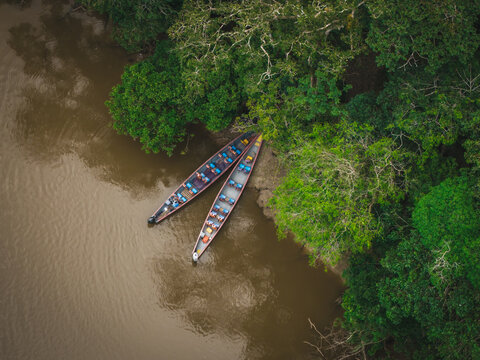 Aerial view of two canoes resting on the tranquil, muddy waters of the river, bordered by the emerald canopy of the Amazon, Tipishca, Sucumbios, Ecuador.