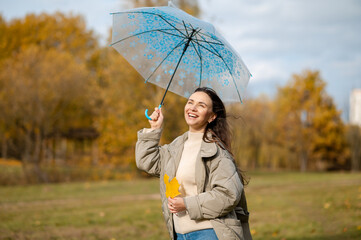 Happy woman with umbrella enjoying autumn sunlight and freedom in the park