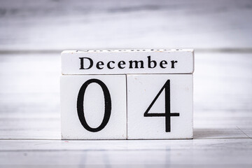 A decorative wooden calendar block displays the date December 04, symbolizing winter and the holiday season. The white background enhances its modern and minimalistic design.