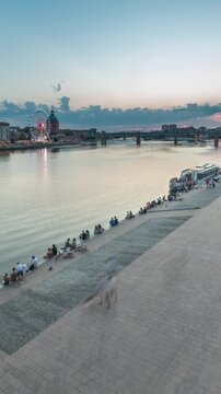 Aerial view of Port de la Daurade park along the Garonne River day to night transition timelapse in Toulouse, France. La Grave Hospital with Saint-Pierre Bridge during sunset with colorful clouds