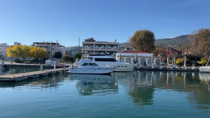 Idyllic waterfront view with yachts and autumn trees in serene harbor setting
