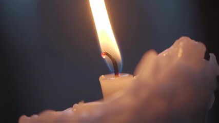 Close-up of a burning candle with a bright flame in the dark. - Powered by Adobe