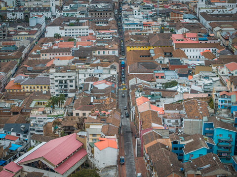 Aerial view of terracotta roofs meet the sky, streets lined with colonial architecture, a vibrant tapestry of urban life unfolds, Quito, Ecuador.