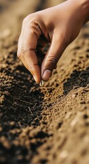 Hand planting a seed in fertile soil for growth.