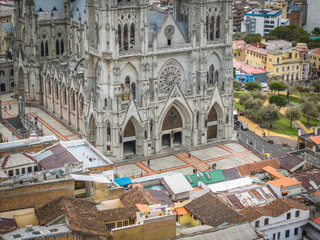 Aerial view of the grand Basilica del Voto Nacional rises majestically, its gothic spires piercing the sky above the terracotta rooftops, Quito, Ecuador.