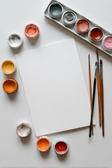 Set creativo di pittura con un foglio bianco, tavolozza da acquerelli con più colori e pennelli di varie dimensioni.