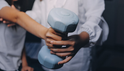 old woman training with physiotherapist using dumbbells at home therapist assisting senior woman with exercises in nursing home elderly patient using dumbbells with outstretched arms no logos no bran