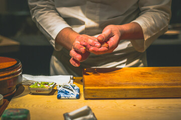 hands of japanese omakase chef preparing sushi at omakase counter