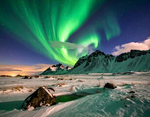 Bright green aurora borealis shines above snow-covered mountains at night.