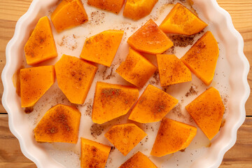 Sweet baked pumpkin slices with cinnamon on a ceramic plate, top view, macro.