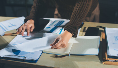Close-up of businessman's hands making notes, mobiles, chart, desk, office