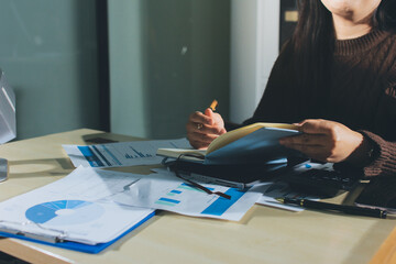 Close-up of businessman's hands making notes, mobiles, chart, desk, office