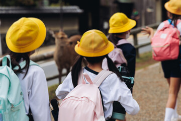 Group of school children students outdoor excursion, guided tour in the city with guide, docent with tourist pupils visitors, wear color caps hats, kids class field trip, urban sightseeing in Japan © tsuguliev