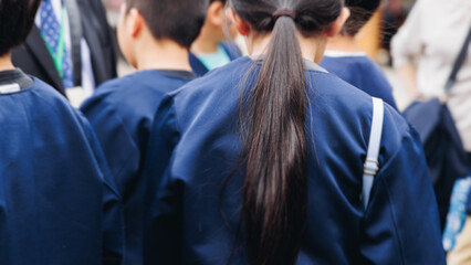 Group of school children students outdoor excursion, guided tour in the city with guide, docent with tourist pupils visitors, wear color caps hats, kids class field trip, urban sightseeing in Japan