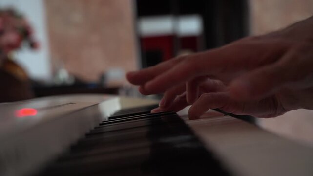Closeup view of hands playing piano with shallow depth of field, selective focus, and soft bokeh. Side angle of domestic music practice