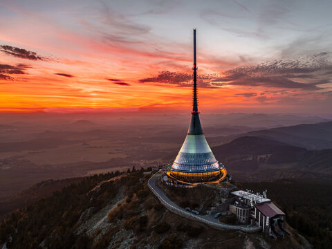 Aerial view of the iconic Jestěd tower piercing the vibrant sunset sky, its unique silhouette a beacon against the fading light, Liberec, Liberecky kraj, Czechia.