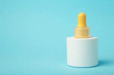 Minimalist white cosmetic dropper bottle on blue background. Elegant mockup for skincare, serum, or beauty branding presentations.