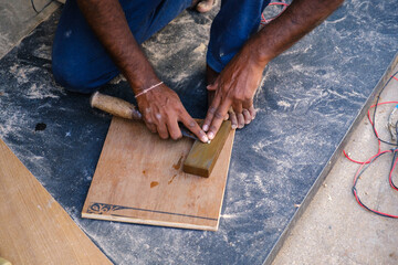 Closeup of Indian artisan hand sharpening a blade on a whetstone, traditional tool maintenance and craftsmanship, showcasing hands-on skill and manual technique in workshop setting.