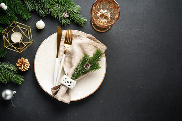 Christmas table setting. Christmas dinner - black plates with cutlery and decorations on black...