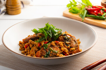 Stir Fried Crispy Basil with Pork and Black Preserved Egg in white plate (Kai Yiew Ma Kra Prao Krob)