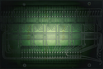 Vintage electronic circuit board illuminated from behind. Close-up of an old printed circuit board backlit to reveal its intricate network of metallic traces and connections.