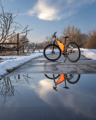 Obraz premium mountain bike on Poudre River Trail near Greeley in Colorado, winter scenery with puddle reflection