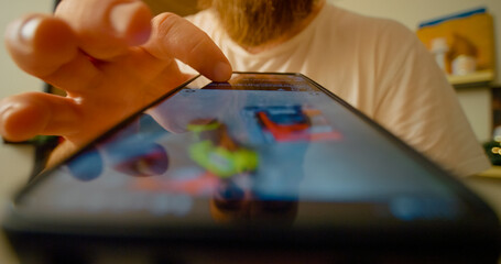 Bearded male scrolling through social media news feed on smartphone, viewing multiple screens with...