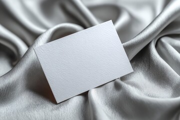 Blank business card mockup displaying elegant textured paper on soft gray silk