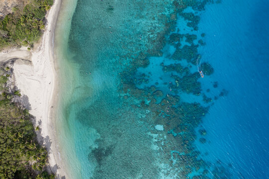 Aerial view of the serene beach meeting the turquoise sea, where the coral reefs paint an underwater tapestry of color, Nadi, Western Division, Fiji.