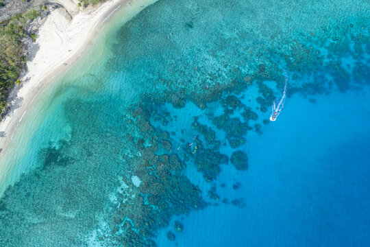 Aerial view of turquoise waters meeting pristine white sands, where the reef's intricate patterns dance beneath the surface, Nadi, Western Division, Fiji.