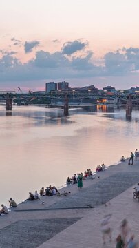 Aerial view of Port de la Daurade park along the Garonne River day to night transition timelapse in Toulouse, France. La Grave Hospital with Saint-Pierre Bridge after sunset with colorful clouds