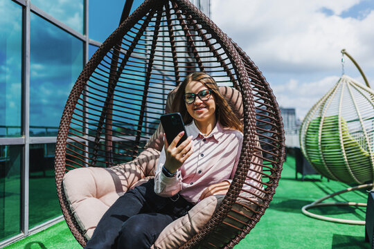 Relaxing on a rooftop with a smartphone while enjoying the sunny sky and a scenic view