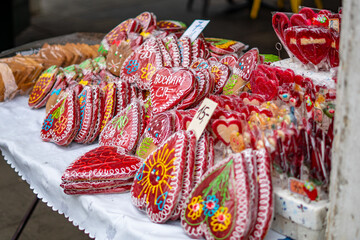 Colorful heart-shaped iced gingerbread cookies displayed at a traditional market stall during a local festive event in the city