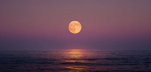 Full moon over water with light reflection and hazy pink/purple sky