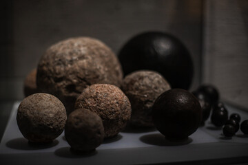 A collection of various antique objects inside a medieval castle: wooden chests, metal locks, ancient tools, sculptures, books, candles, and decorative elements. Warm light highlights textures, materi