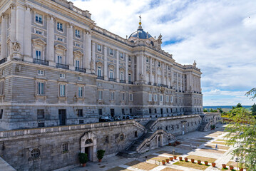 Majestic view of Madrid’s Royal Palace, captured from a medium distance, showcasing its grand façade, elegant symmetry, and regal architectural detail, subtle charm