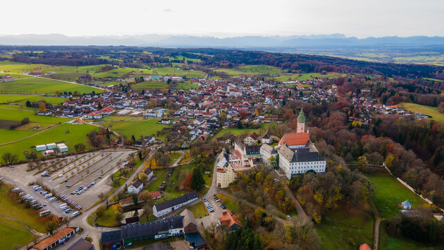 Aerial view of the majestic Andechs Abbey perched atop a hill, overlooking the quaint town nestled amid a tapestry of vibrant autumn foliage, Andechs, Bayern, Germany.