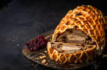 A luxurious Three Bird Wellington featuring layers of turkey, duck, and pheasant wrapped in golden puff pastry with herbed stuffing. Sliced to reveal the colourful cross-section and served on a rustic