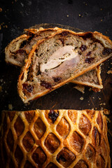 A luxurious Three Bird Wellington featuring layers of turkey, duck, and pheasant wrapped in golden puff pastry with herbed stuffing. Sliced to reveal the colourful cross-section and served on a rustic